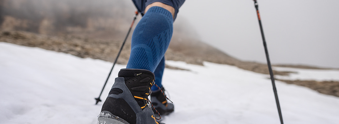 Merino hiking socks light blue while hiking Person hikes via snow covered rocks she wears merino hiking socks