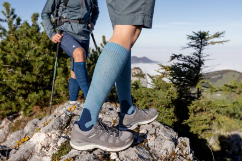 Woman with green hiking socks steps on a rock at dusk