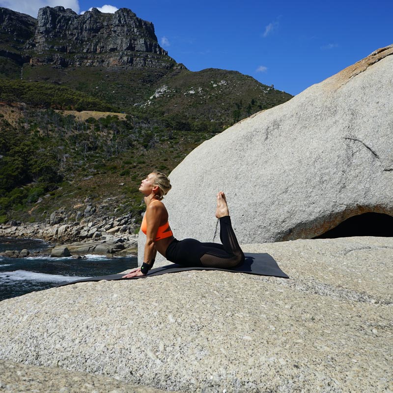 Woman at the outdoor yoga in the Königskobra pose has supported her hands and stretched her feet vertically upwards