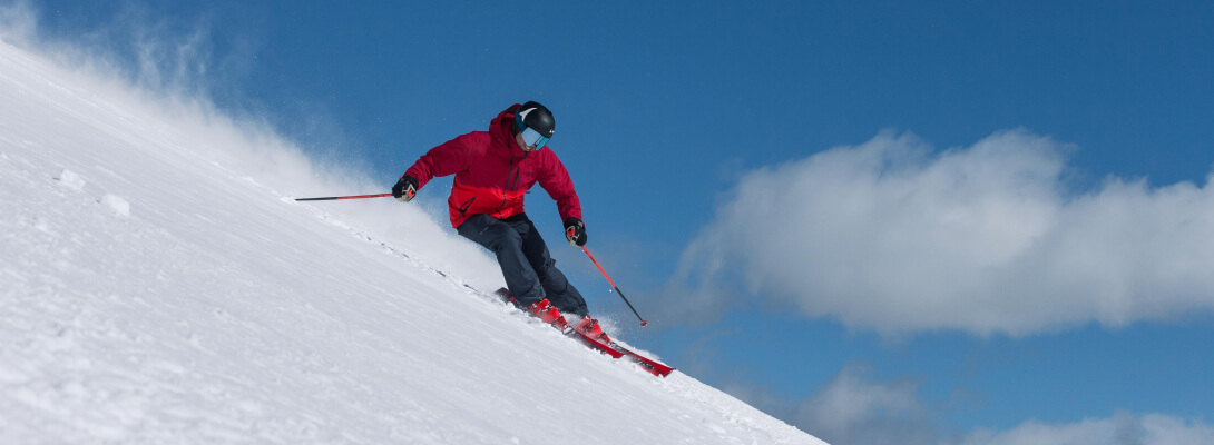 Merino ski socks for alpine skiing Skier with red jacket in powder snow on downhill skis