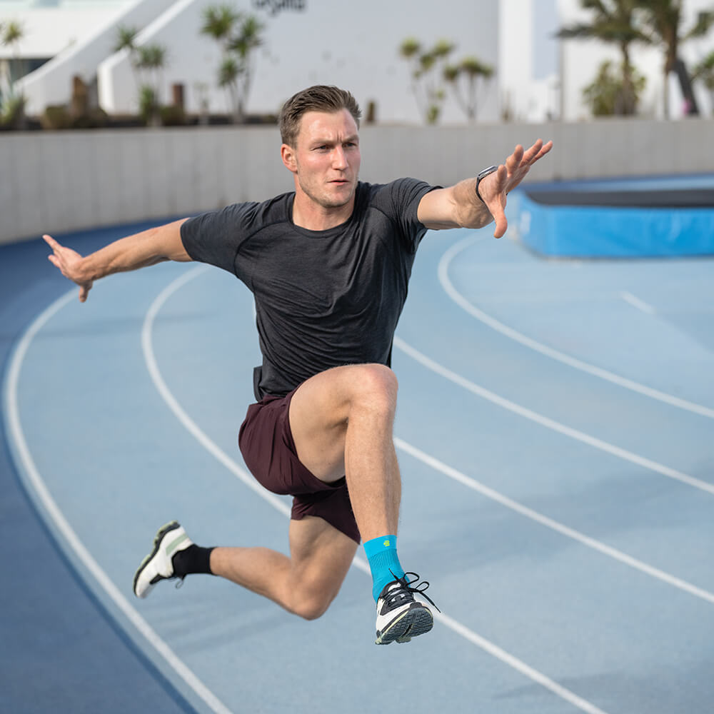 Runner with compression ankle support in hurdle jumping