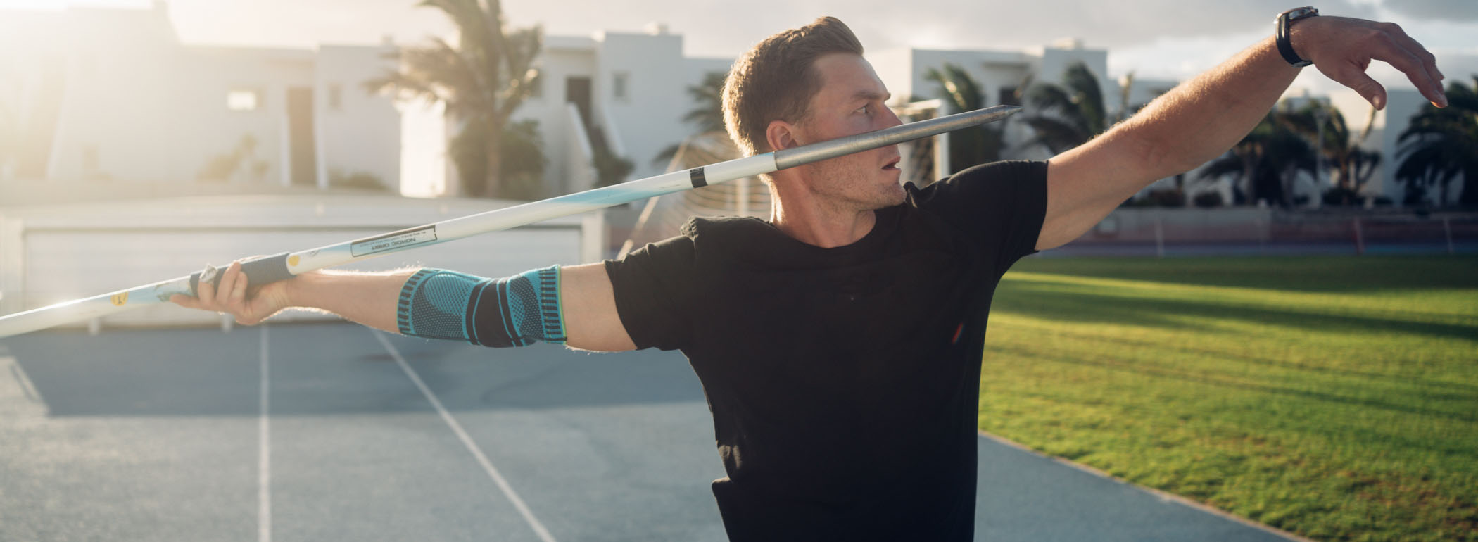 Precision in Motion: Achieve Your Throwing Record with Stable Arms and Perfect Support! A javelin thrower in the stadium preparing for a powerful throw. He is wearing a blue elbow support brace on his right arm, providing stability, compression, and optimal protection during intense throwing motions.