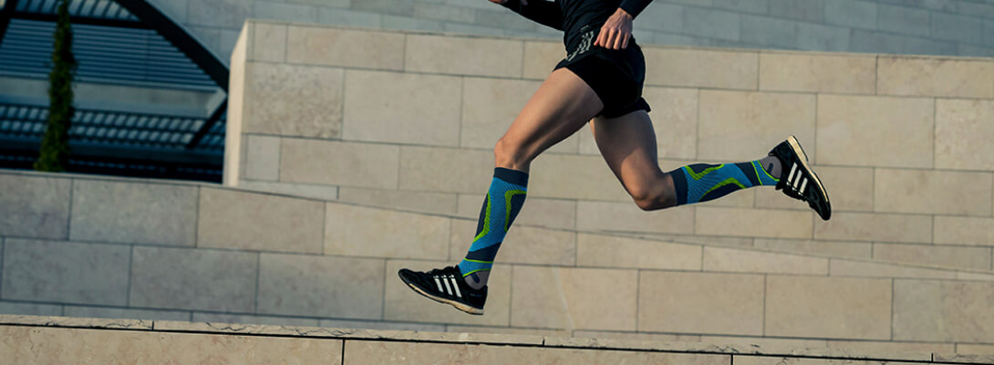 Compression socks blue while running in the city Runner with compression socks to run in front of a stone wall