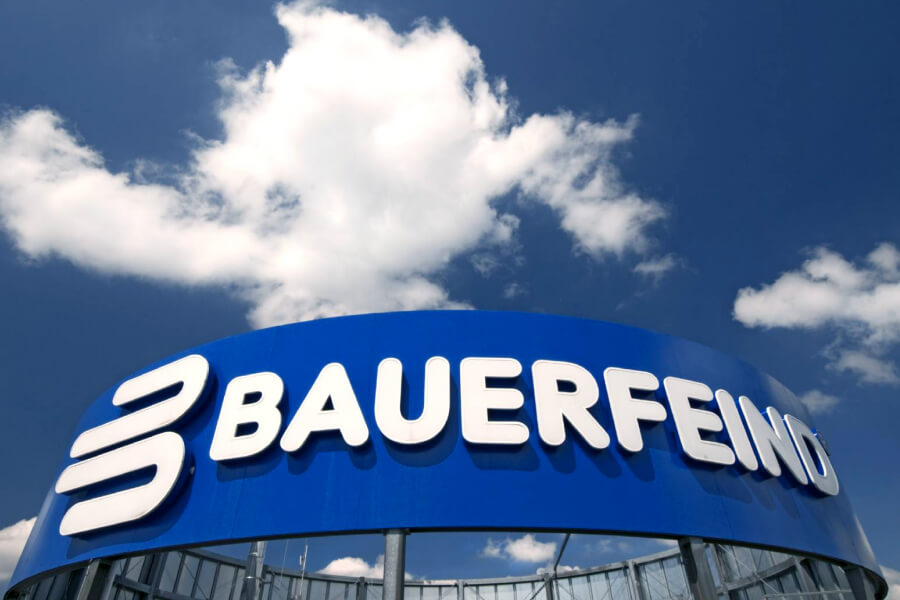 Bauer enemy lettering on a blue surface on the roof of a high -rise building above it blue sky with a cloud