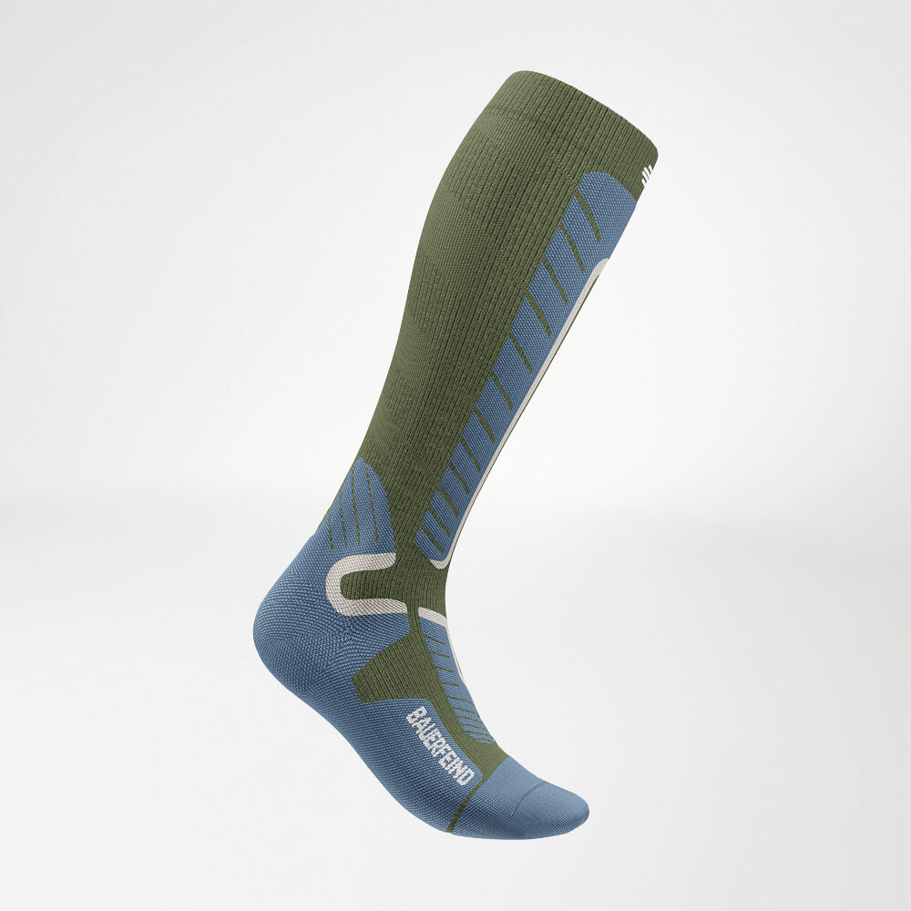 Side view of a green knee-high ski compression sock featuring reinforced knit pattern for optimal stability and comfort during winter sports.