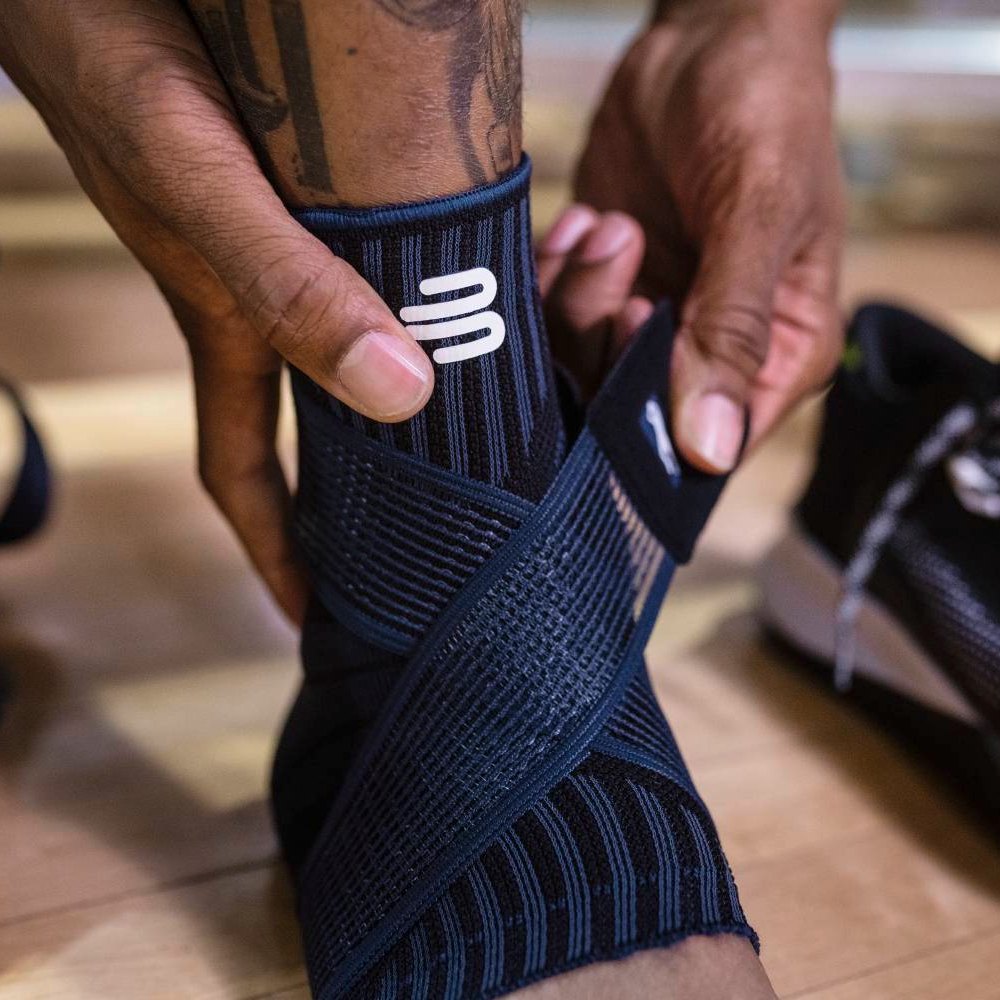 Alt-Text: Close-up of a black ankle support with integrated support zones and an elastic strap for individual adjustment.