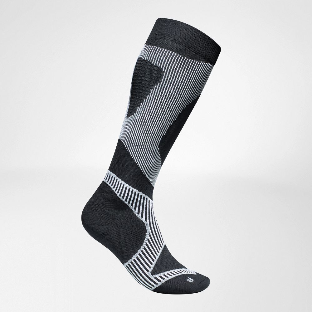 Lateral complete view of the black and white compression stockings to run