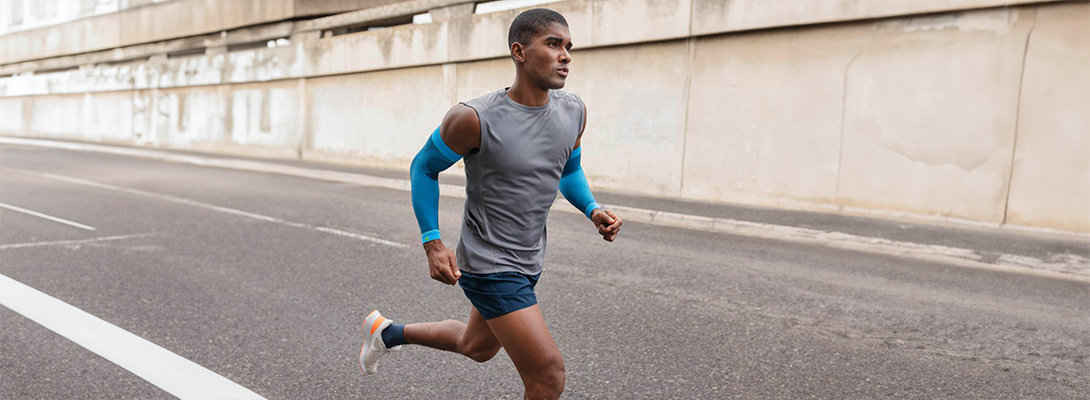 Arm Sleeve while running Runner with blue arm sleeves runs through the city on a street