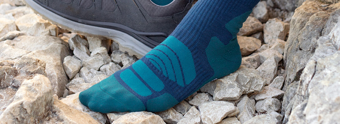 Merino hiking socks dark blue during a hiking break Foot in a merino hiking socks on a stony surface