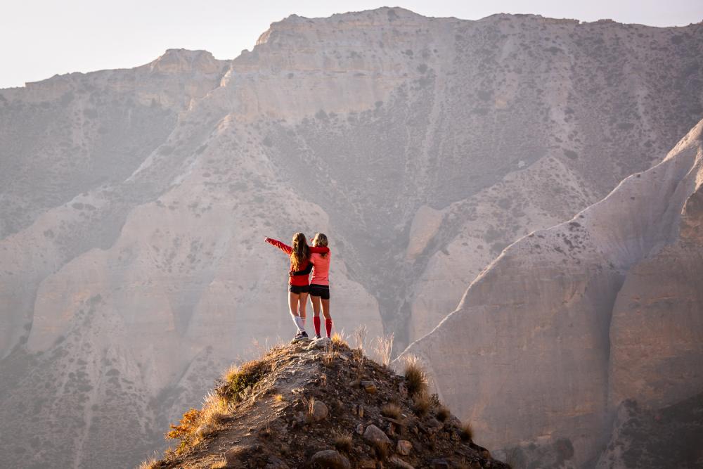 Two women cheer on a mountain summit