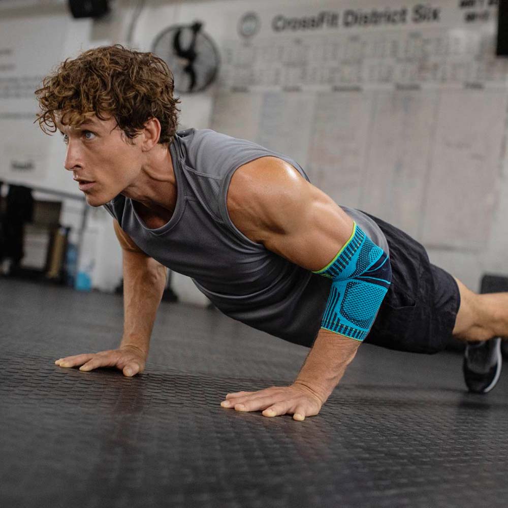 Young man does push-ups in a gym and wears an elbow bandage in Rivera